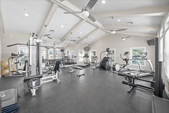 A spacious gym with various exercise equipment and a ceiling fan.